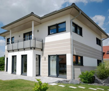 Einfamilienhaus mit weißer Fassade und sandfarbenen Querstreifen als Akzent