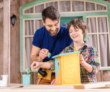 Vater und Sohn bemalen ein selbst gebautes Vogelhaus