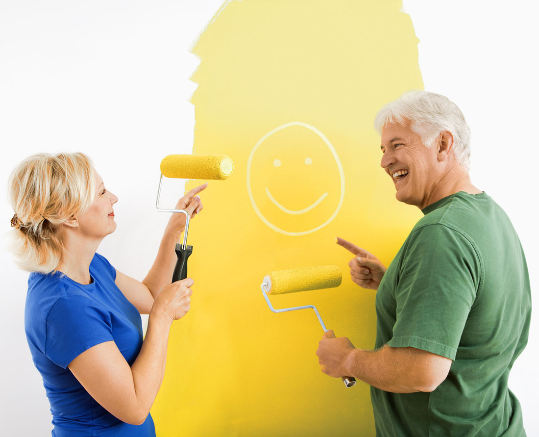 Ein Ehepaar streicht die Wand gemeinsam gelb und freut sich über das Ergebnis