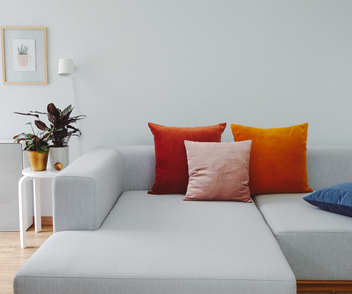 Ein Wohnzimmer mit grauer Wand und einer Couch mit orangefarbenen Kissen