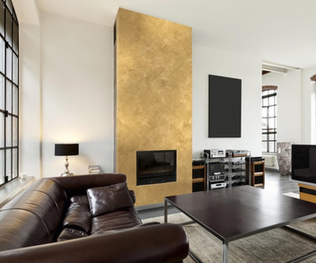 Wohnzimmer mit dunkelbraunen Möbeln und goldfarbener Wand als Akzent