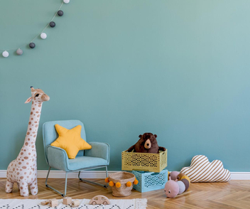 Ein Kinderzimmer mit Spielzeug, einem Stuhl und einer Wand im Farbton Mint. 