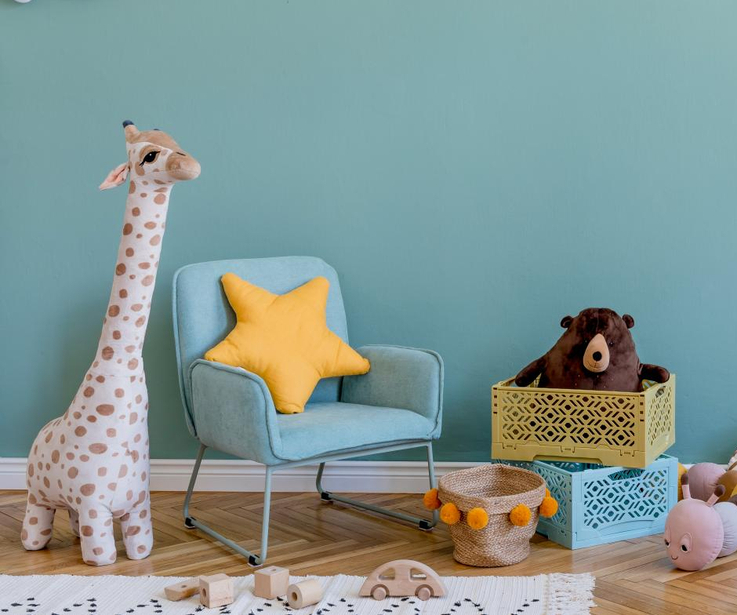 Ein Kinderzimmer mit Spielzeug, einem Stuhl und einer Wand im Farbton Mint. 