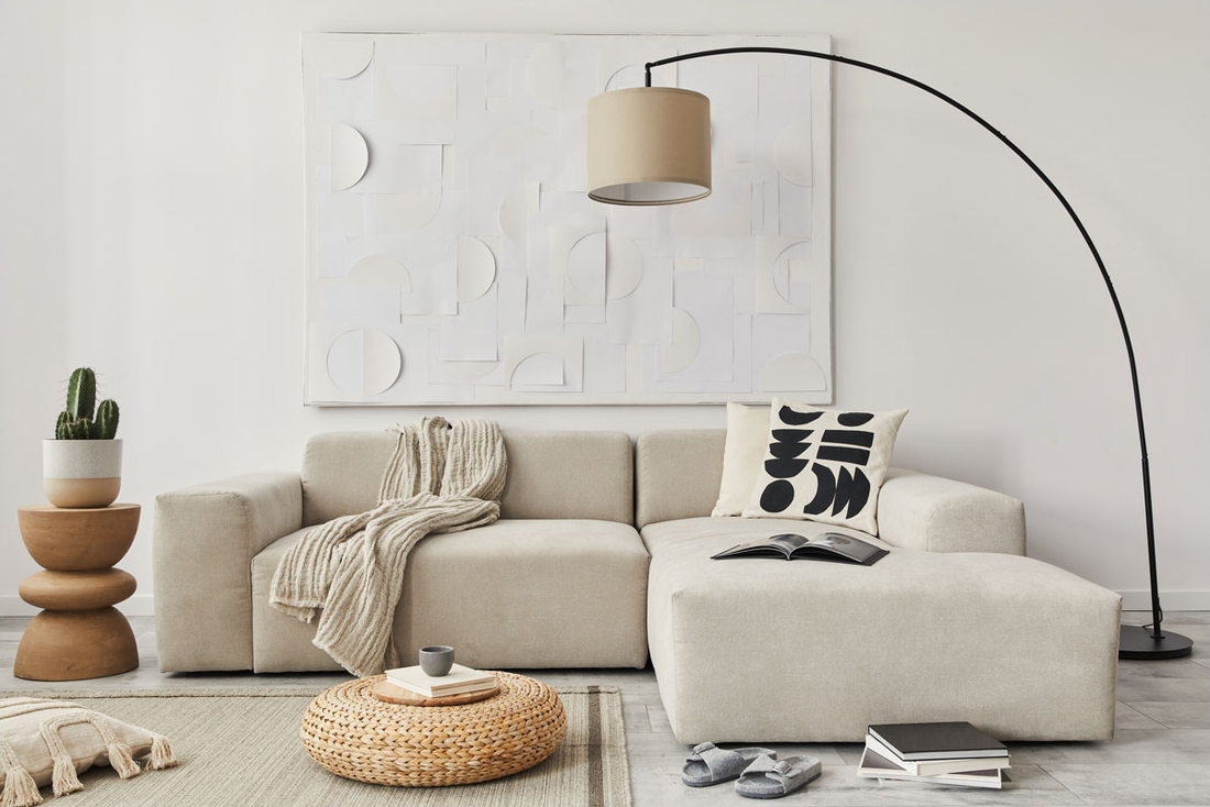 Ein Wohnzimmer mit beigefarbener Couch und farblich abgestimmter Decke und Kissen. 