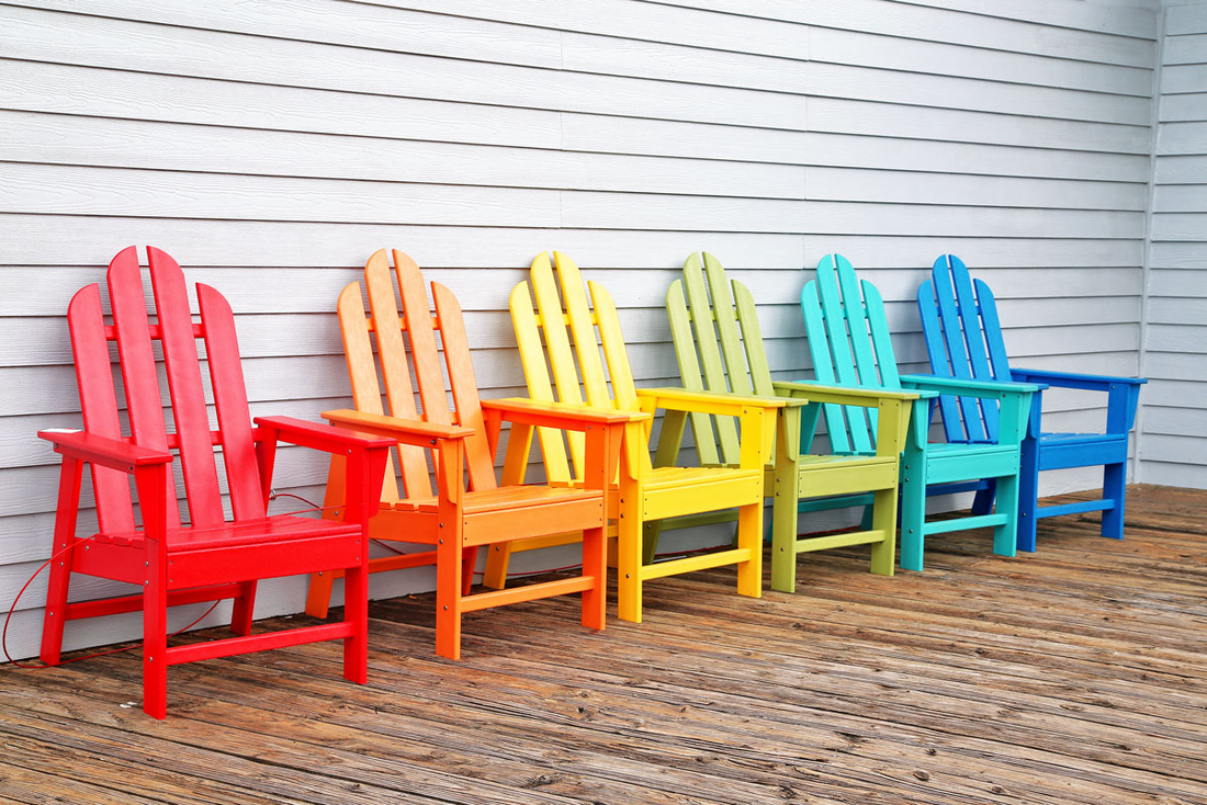 Bunt lackierte Stühle, die auf einer Terrasse stehen