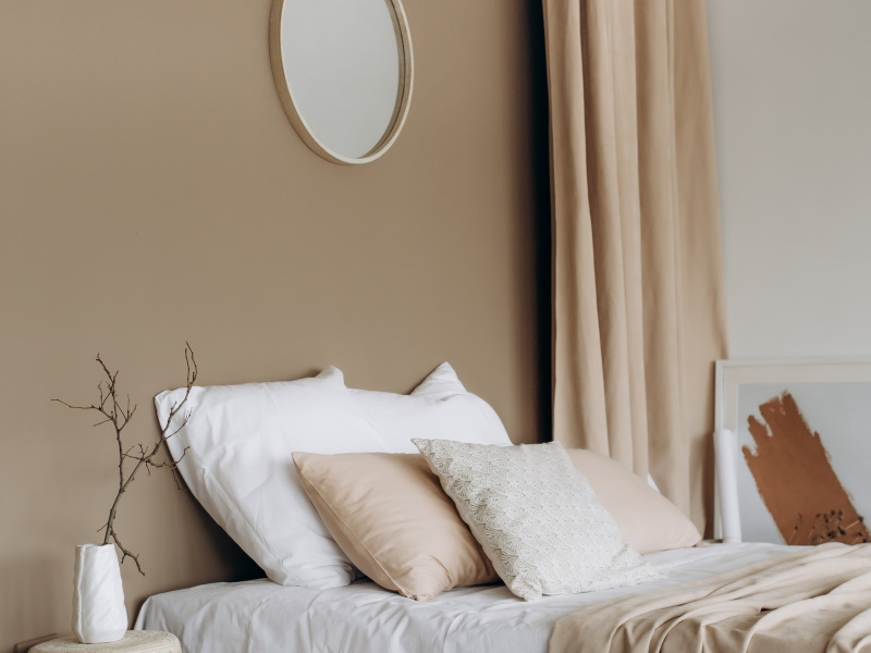 Detailaufnahme von braun gestrichener Schlafzimmerwand und einem Bett